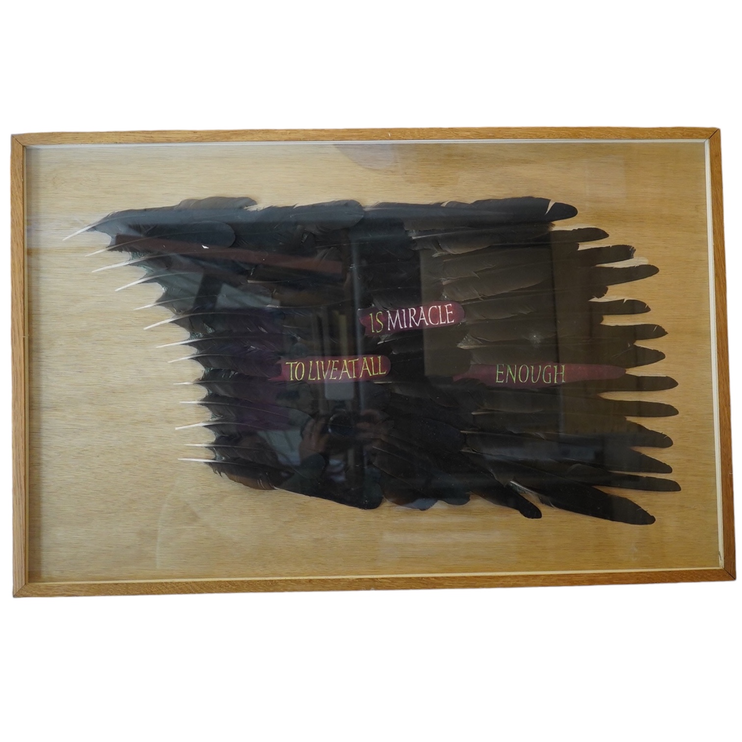 A framed American feather appliqué with message “To Live At All Is A Miracle Enough”, 84cm high, 53wide. Condition - good